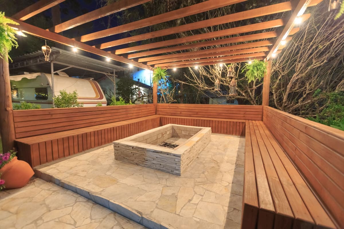 An unlit fire pit surrounded by wooden benches at dusk