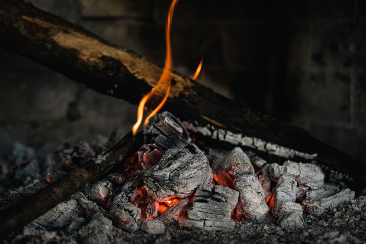 A wood fire burning low in a metal bowl outdoors