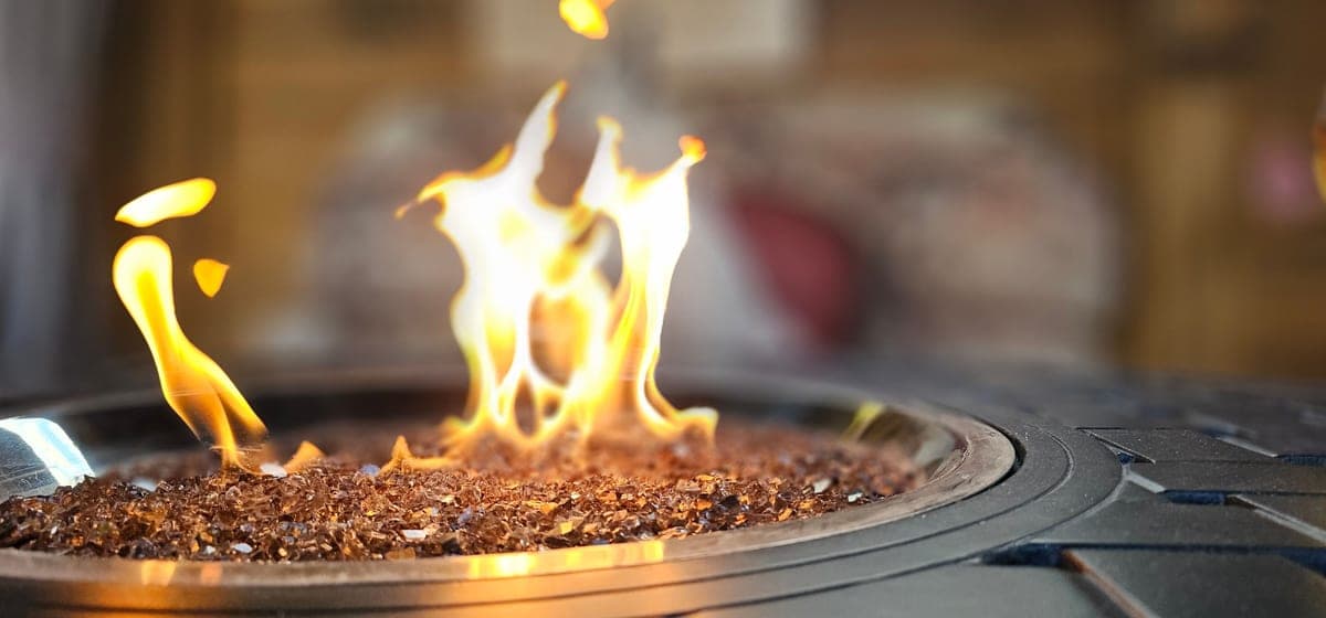 Two outdoor fires burning in metal bowls at dusk