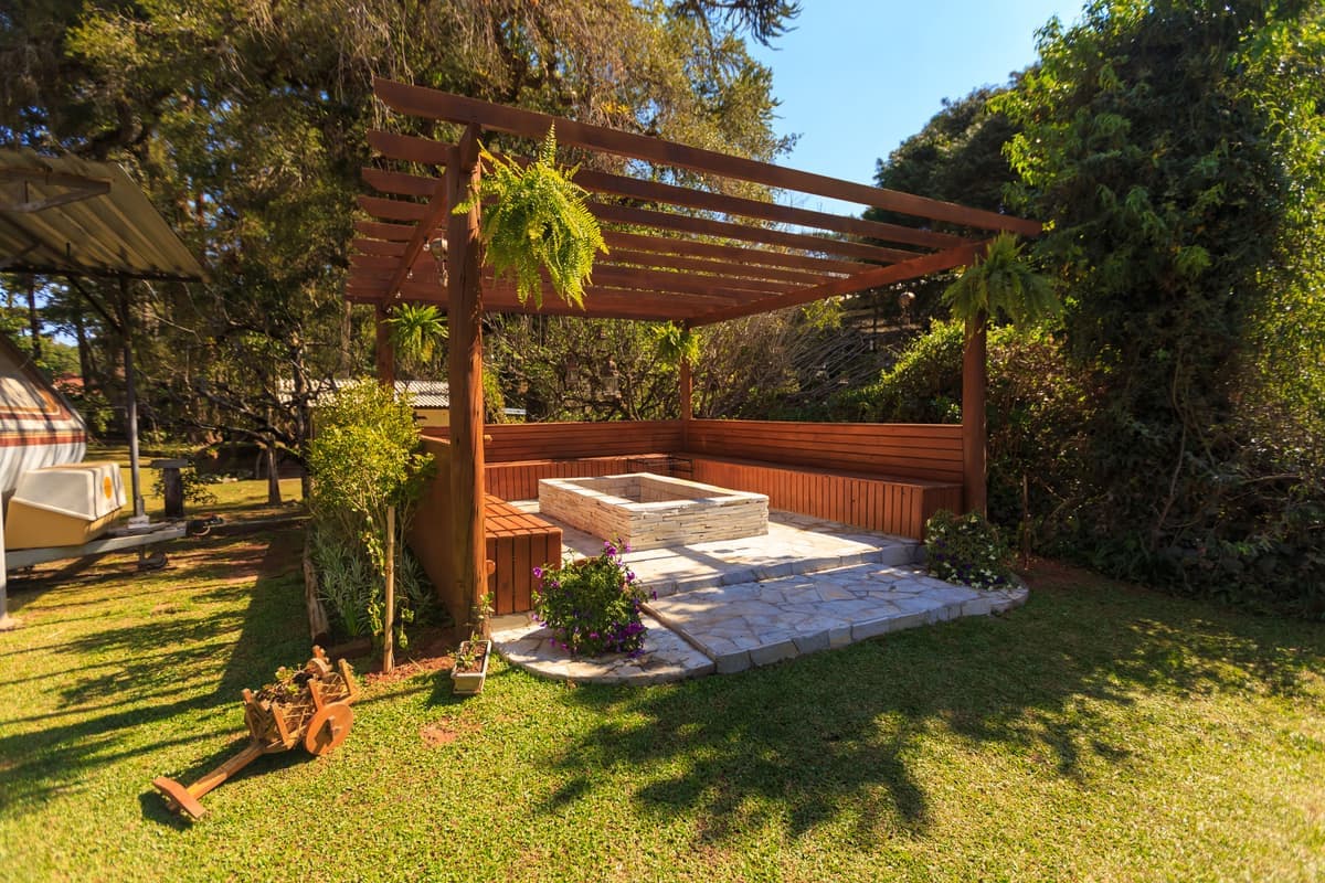 An open-slatted timber pergola over a stone patio and built-in seating