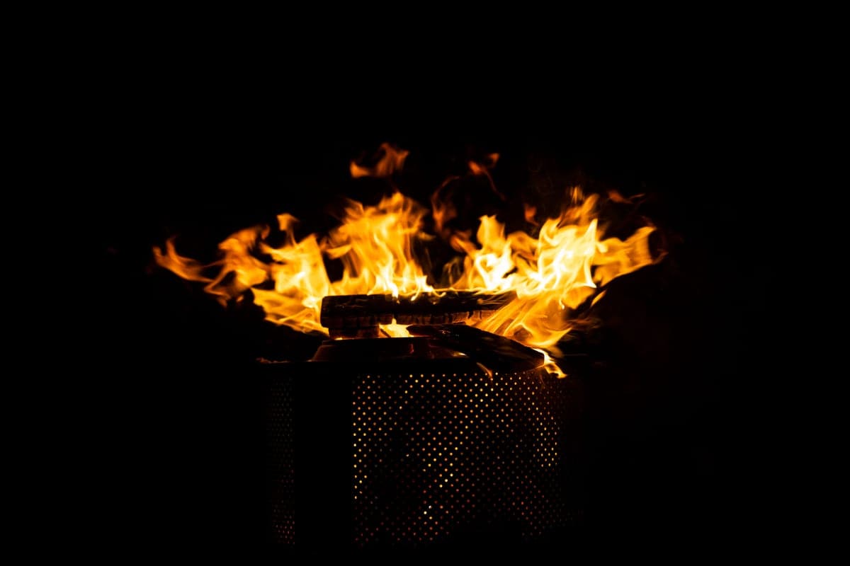 Flames rising from a steel fire pit at night