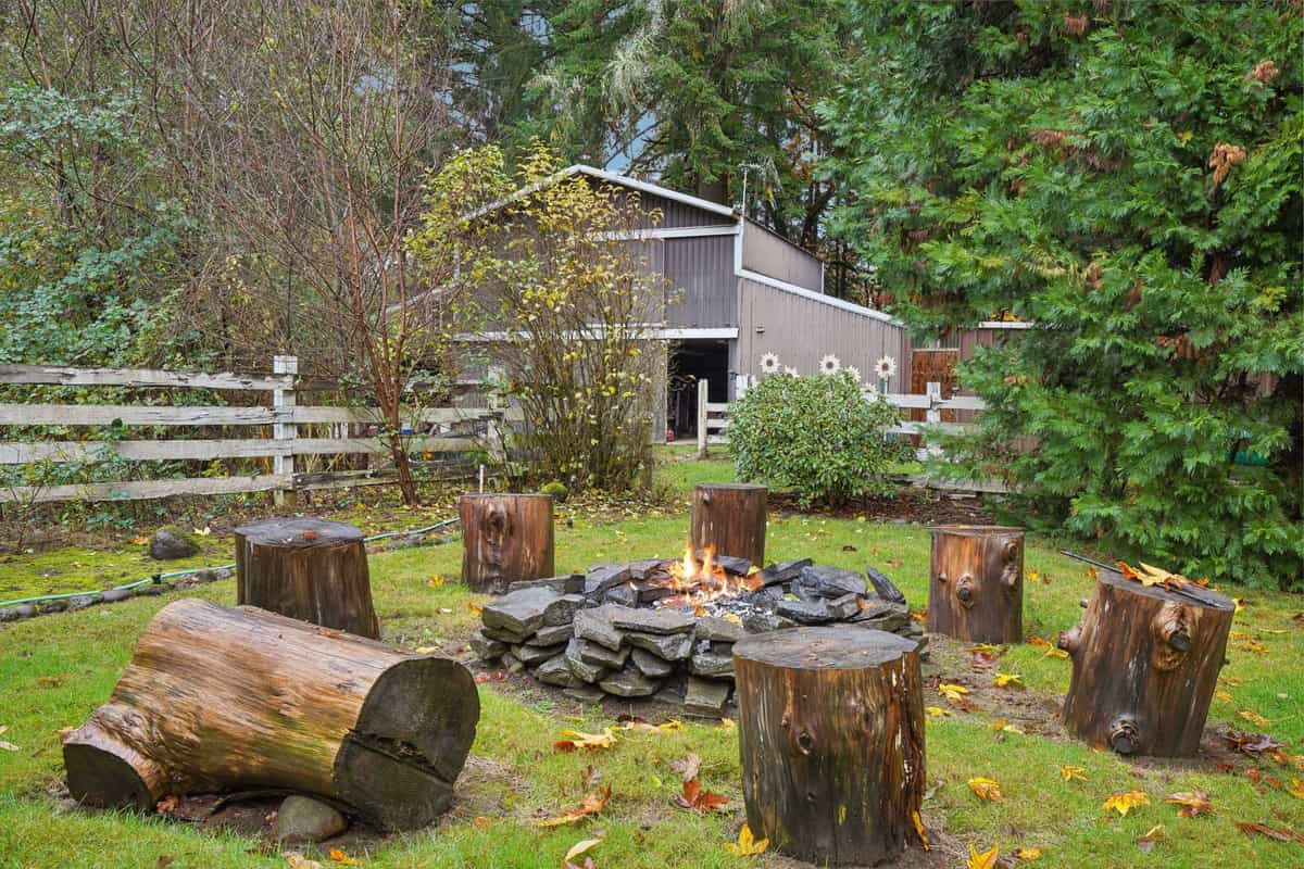 A rustic backyard fire pit ringed with stone and log seats