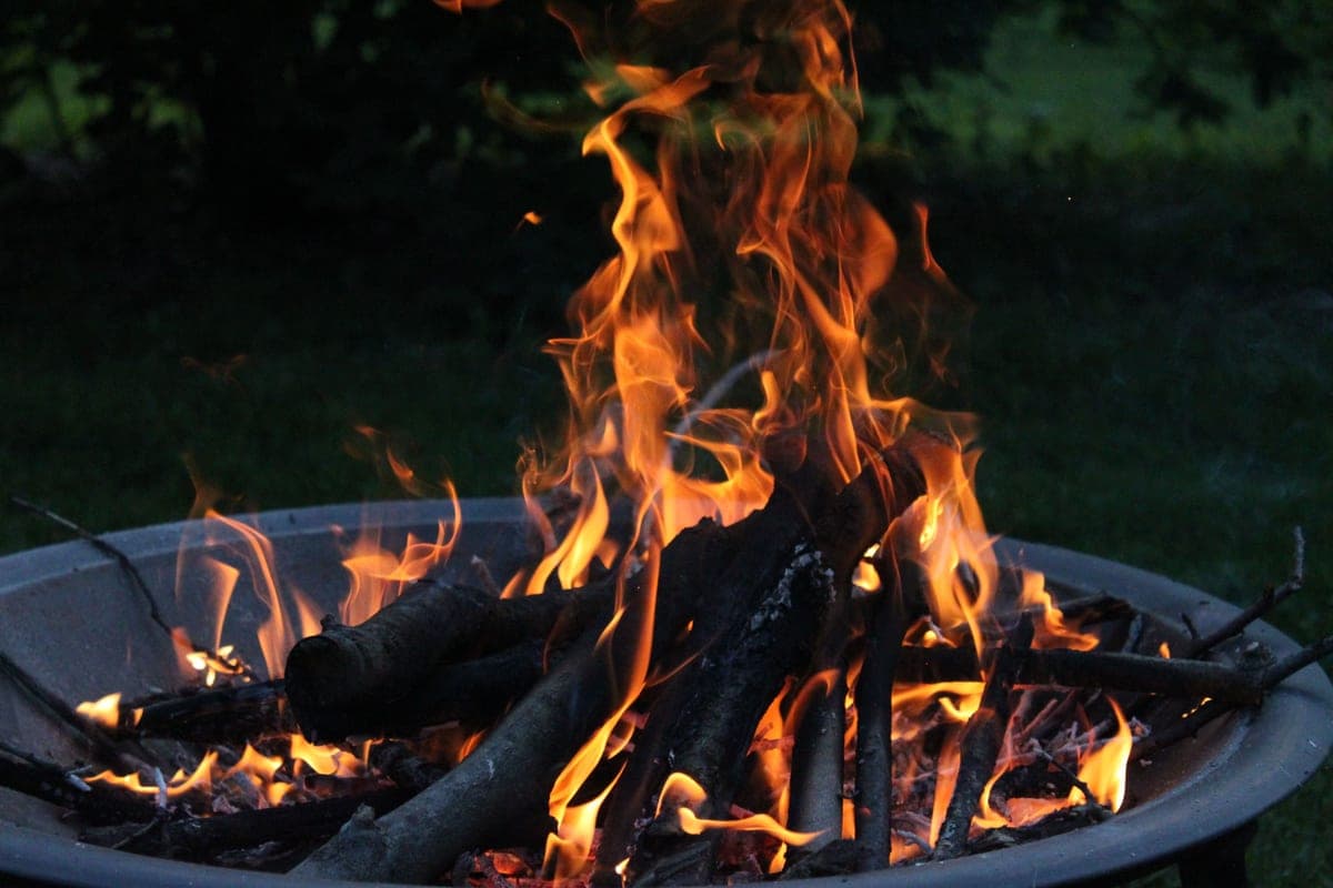 A stainless steel fire bowl with a wood fire burning after dark